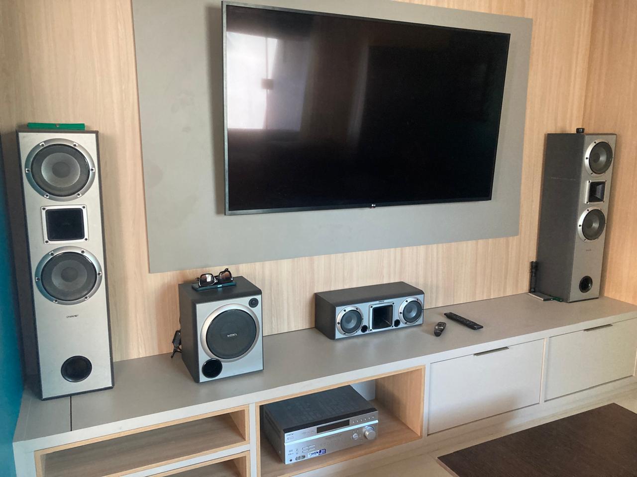 TV e sistema de home theater instalados em um painel de madeira